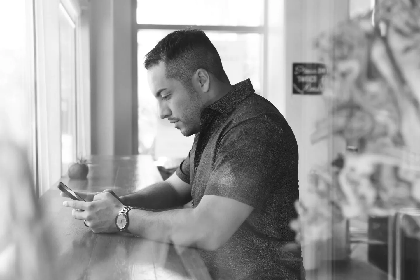 Business owner checking their phone at a cafe — Knowledge Catalog helps you get found by AI search.